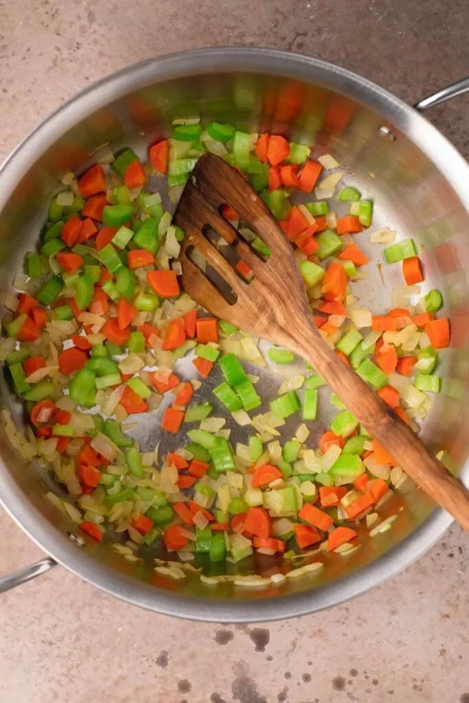 mirepoix cooked in a large pot with a wooden spoon