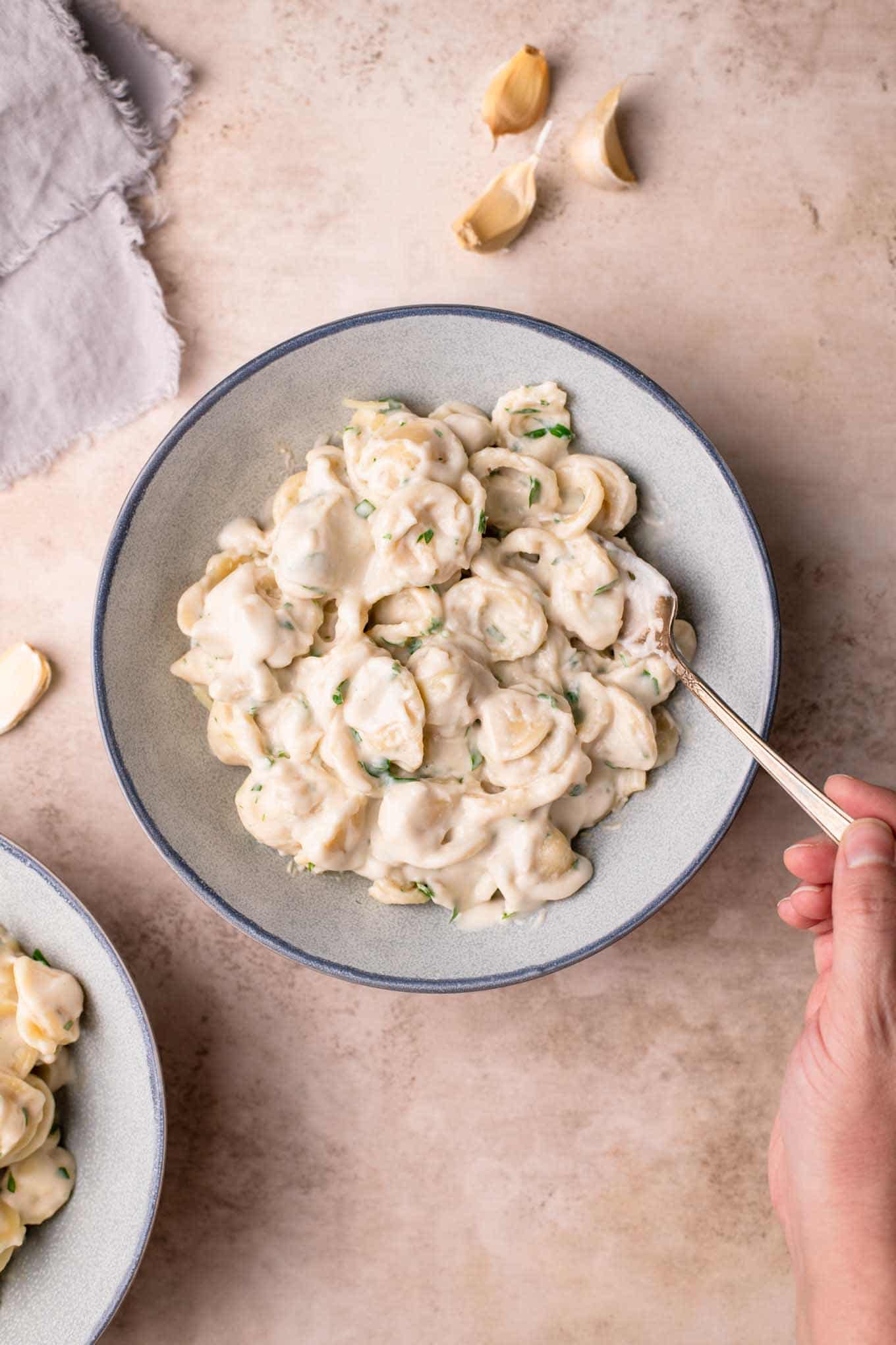 noodles in a bowl with a hand scooping a fork in the bowl