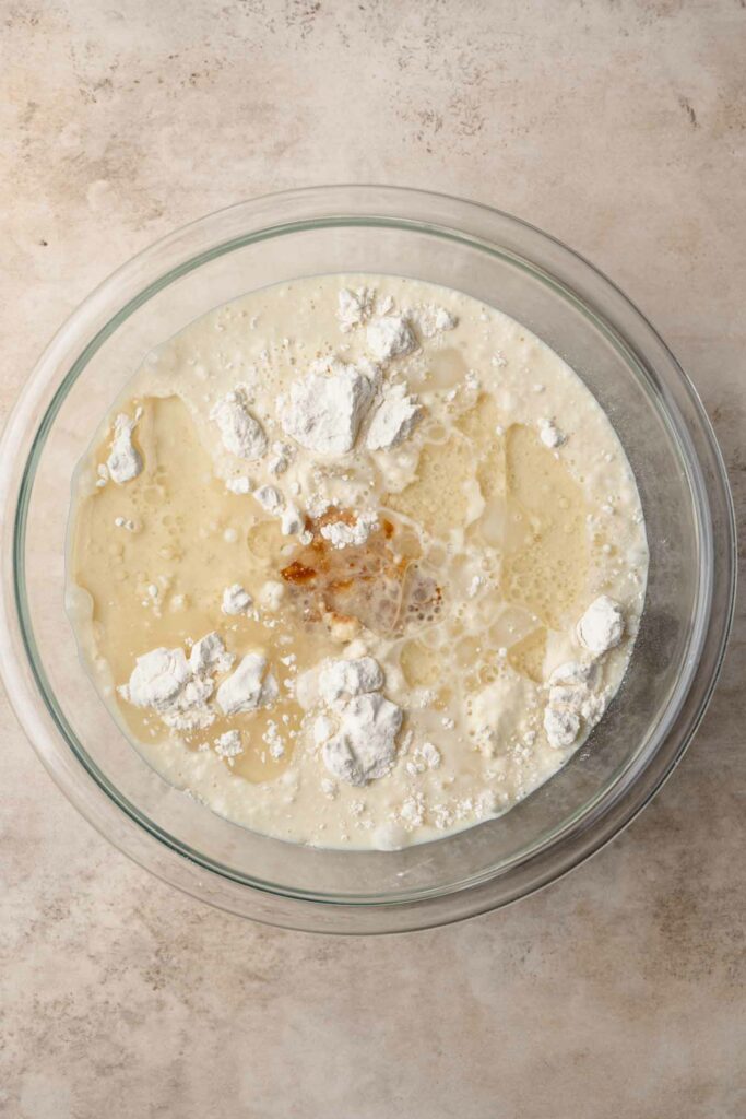 waffle batter ingredients all added to a glass mixing bowl, not yet mixed together