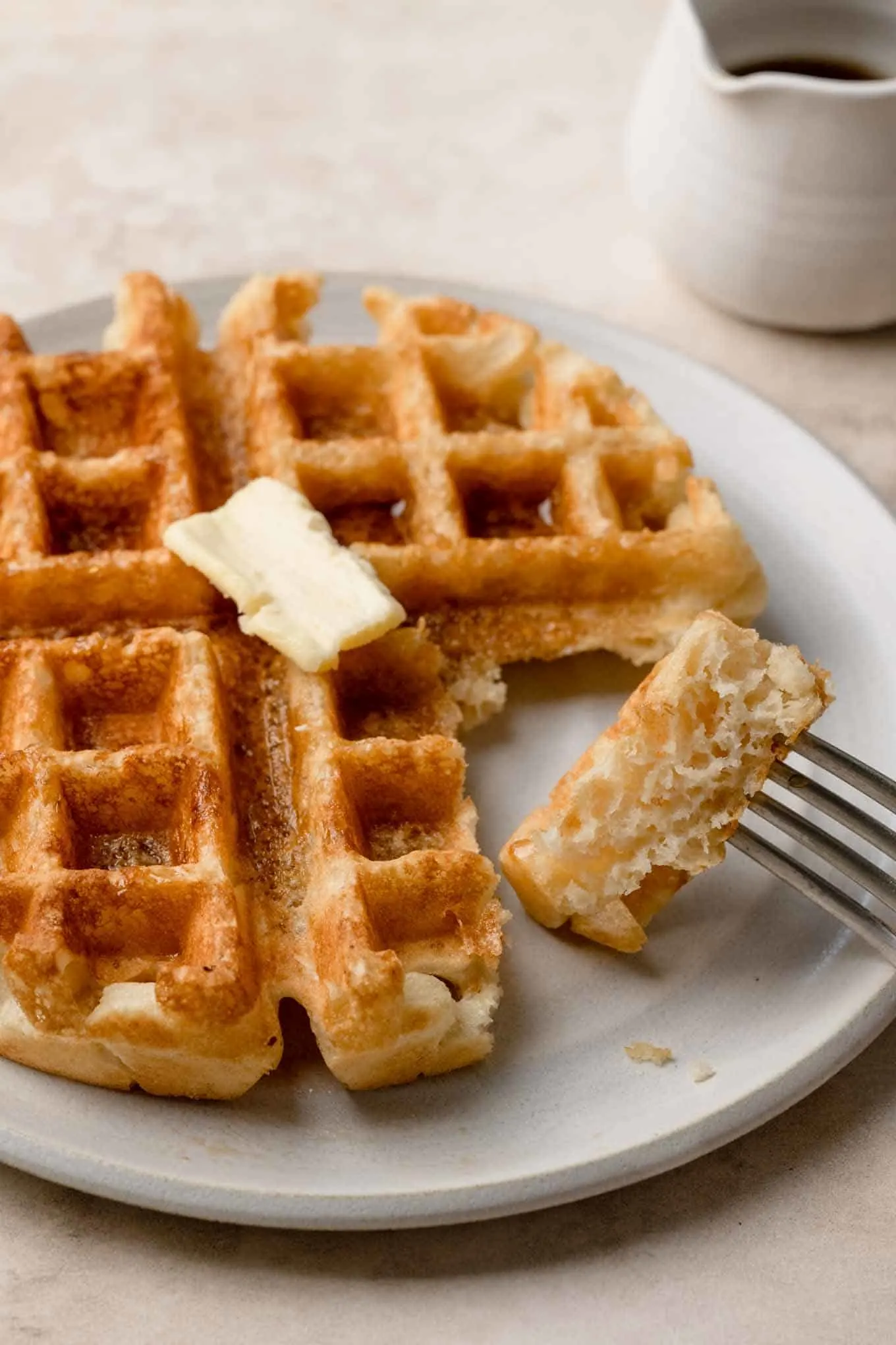 a piece of vegan Belgian waffle speared onto a fork showing the texture of the waffle