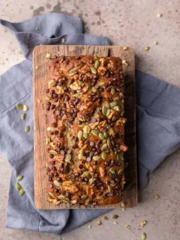 loaf of vegan chocolate chip banana nut bread on a cutting board