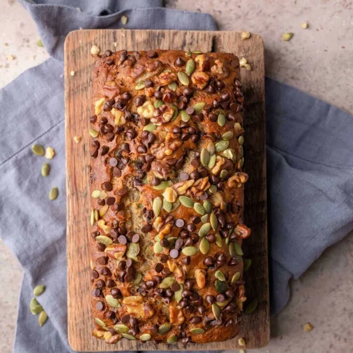 loaf of vegan chocolate chip banana nut bread on a cutting board