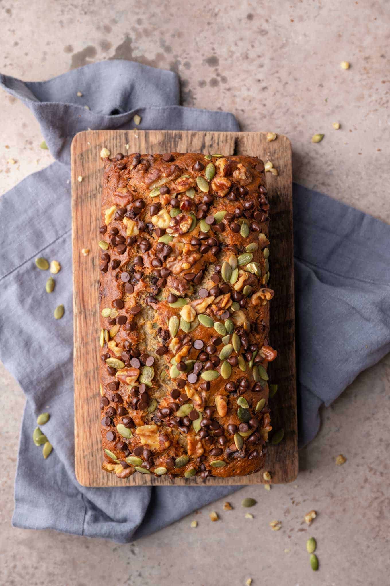 loaf of vegan chocolate chip banana nut bread on a cutting board